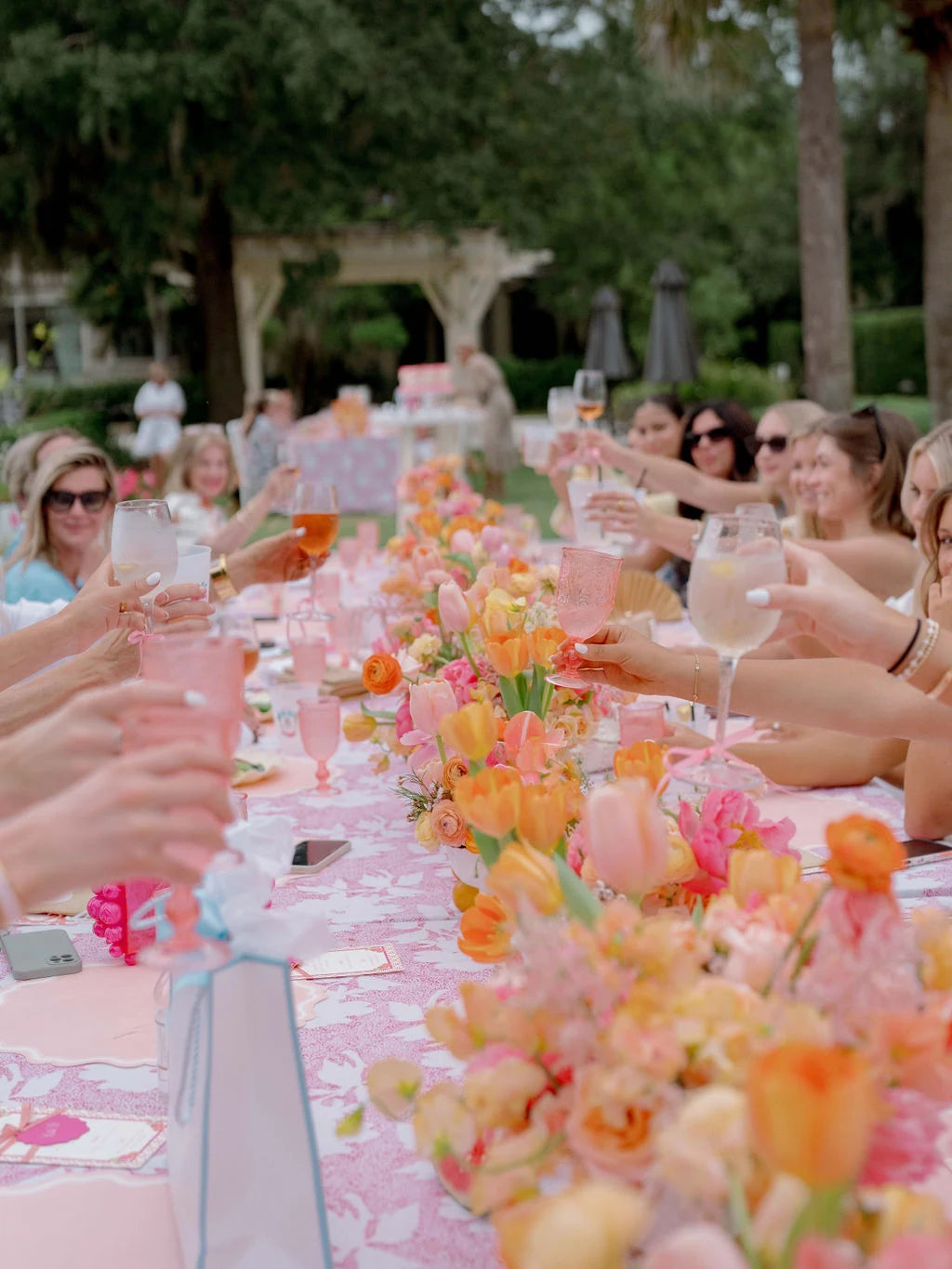 Guests toasting at a garden table filled with pink and orange flowers