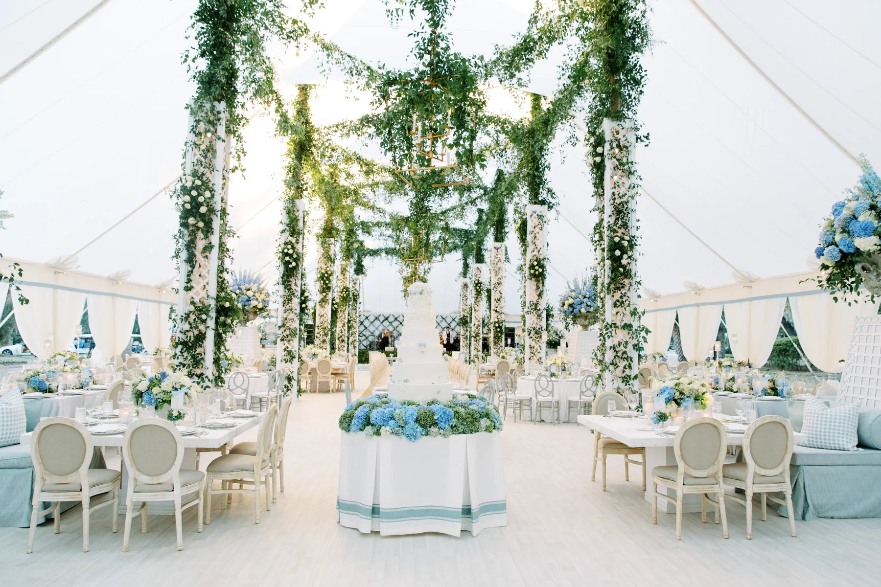 White flowers and climbing greenery throughout a tented wedding reception