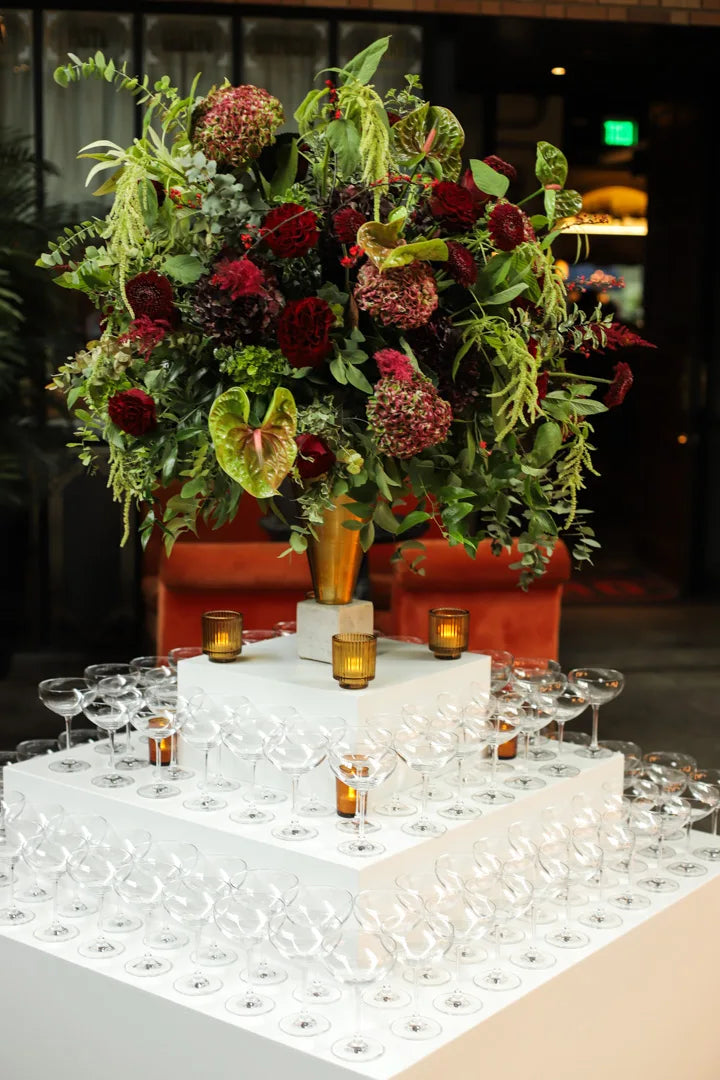 Red and green event flowers beside a champagne tower