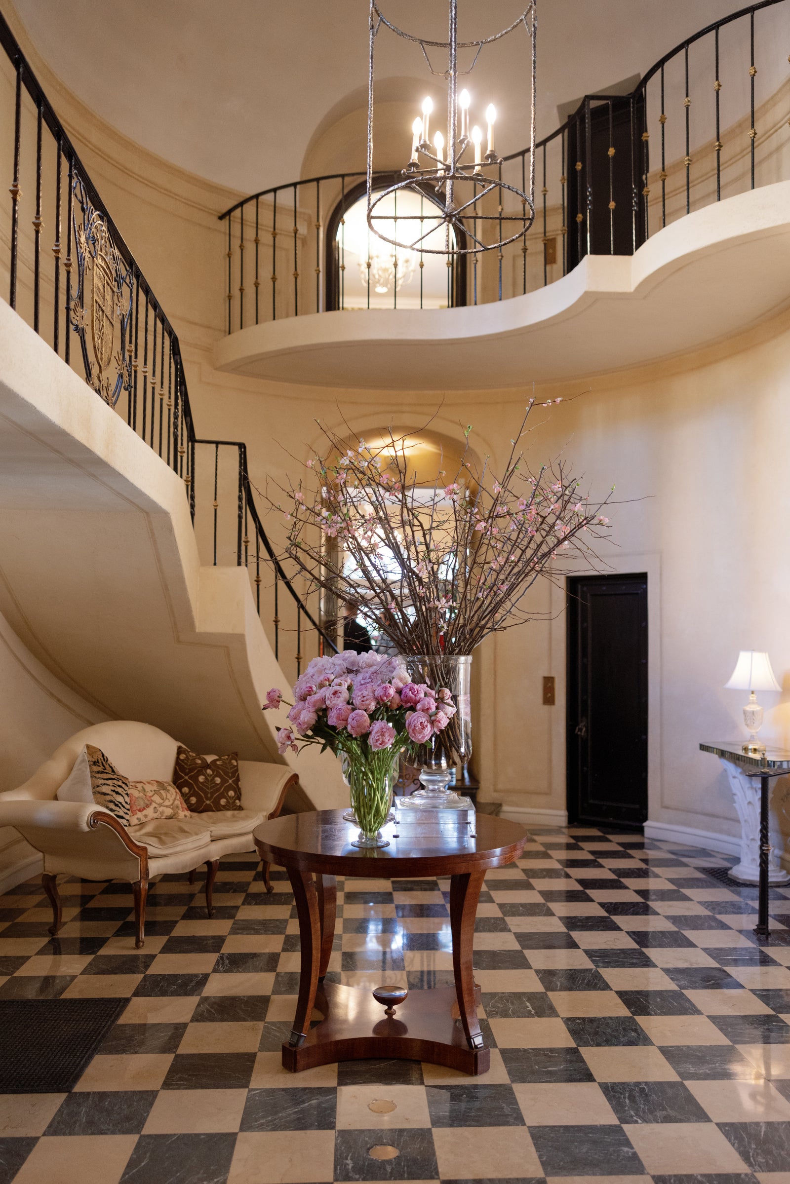 Pink flowers and flowering branches beneath a sweeping staircase